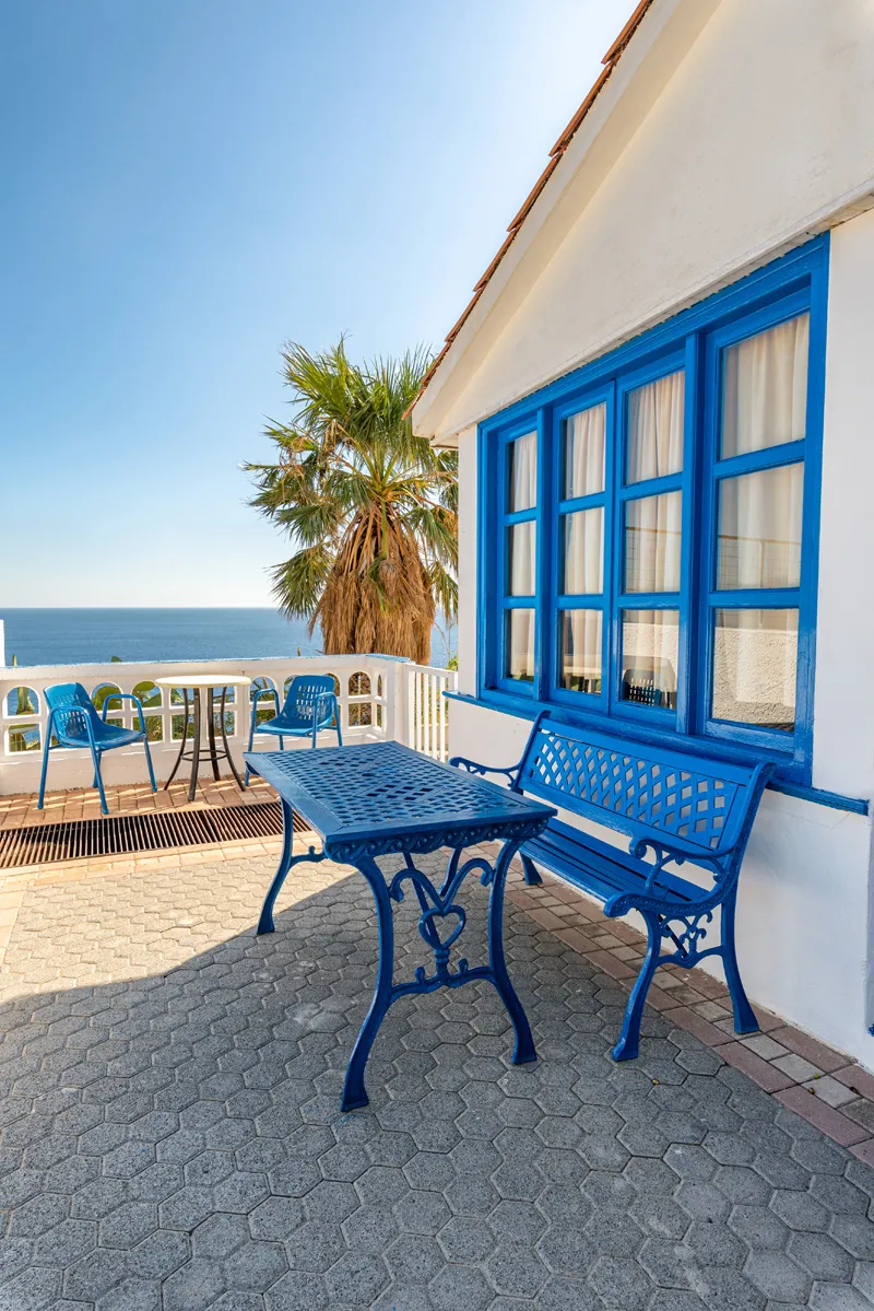 A blue-framed terrace with a table looking over the sea